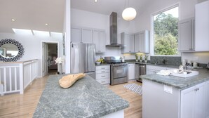 A modern kitchen with grey cabinets, stainless steel appliances, and a large island. - Elegant Gated Beach Compound (Stinson Beach)