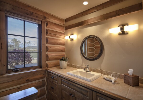 Un baño con paredes de madera, un ventanal grande, un lavabo y un espejo.