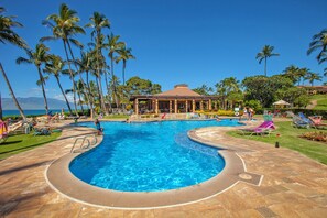 A swimming pool with palm trees and lounge chairs.
