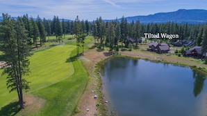Un campo de golf con un estanque, rodeado de árboles y casas.