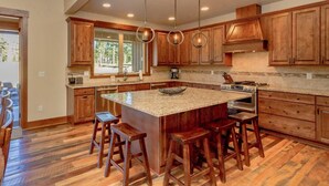 Una cocina amplia con armarios de madera, una isla grande con taburetes e iluminación colgante moderna.