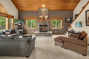 A spacious living room with a stone fireplace, large windows, and a cozy seating area.