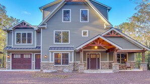 A two-story house with a gabled roof, a front porch with a bench, and a garage.