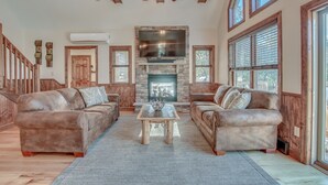 A spacious living room with a fireplace, leather sofas, and a ceiling fan.