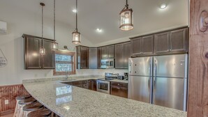 A kitchen with granite countertops, stainless steel appliances, and wooden bar stools.