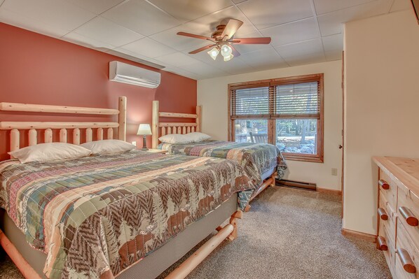 A bedroom with two beds, a ceiling fan, an air conditioner, and a window with blinds. - Summit by PMR, 8BR Guest Favorite, Elevator, Handicap Accessible, Sleeps 26 (Lake Harmony)