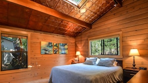 Ein gemütliches Schlafzimmer einer Holzhütte mit einem großen Bett, zwei Nachttischlampen und Bildern an den Wänden.