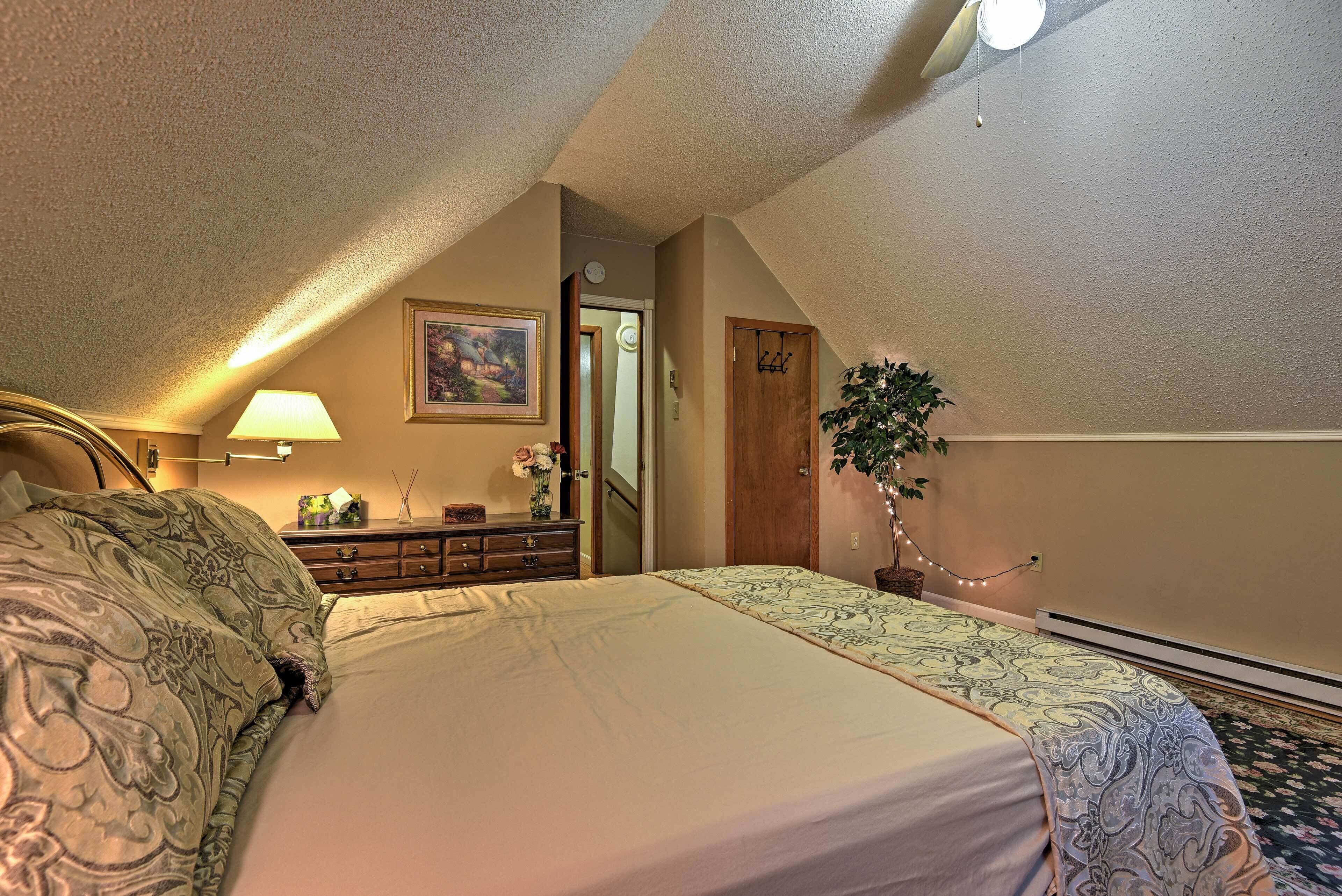 Ein Schlafzimmer mit Bett, Kommode, Spiegel und einer Tür zu einem anderen Raum.