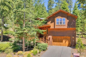 Une cabane en bois avec un garage, entourée d’arbres.