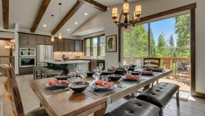 A spacious kitchen with a large island, modern appliances, and a dining area set for a meal. - In the Wild Woods - TLUXP (Tahoe Vista)