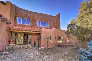 Una casa rústica con techo de tejas, puerta de madera y un pequeño jardín con un camino de piedra.