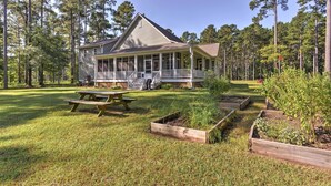 Een huis met een veranda, een picknicktafel en verhoogde moestuinbakken.
