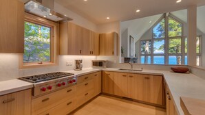 Eine moderne Küche mit Holzausbau, einem Gasherd, einer Mikrowelle und großen Fenstern mit Blick ins Freie.