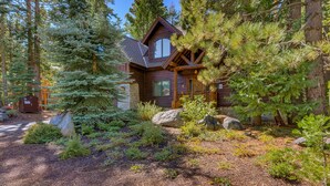 A cabin surrounded by dense forest, with a prominent rock in the foreground and a clear sky above. - Tippy Canoe By Tahoe Getaways - Hot Tub & Sauna + EV Charger (Tahoma)