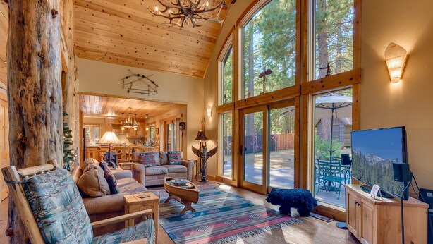 A spacious living room with a large wooden ceiling, a cozy fireplace, and a television. - Tippy Canoe By Tahoe Getaways - Hot Tub & Sauna + EV Charger (Tahoma)