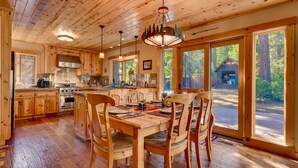 A spacious kitchen with wooden cabinets, a large island, and a dining area with chairs. - Tippy Canoe By Tahoe Getaways - Hot Tub & Sauna + EV Charger (Tahoma)
