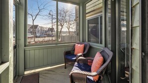 Une véranda avec des fauteuils en osier et une vue sur les maisons et les arbres.