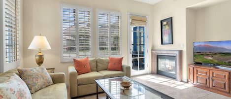 A living room with a sofa, a glass coffee table, a fireplace, and a television.