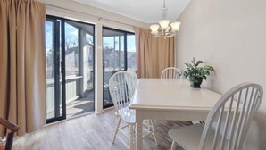 A dining area with a white table and chairs, a chandelier, and a potted plant. - 107 Pointes North Inn | Downtown Charlevoix Gem | Indoor/Outdoor Pool (Charlevoix)