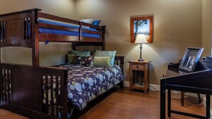 A room with a bunk bed, a desk, a lamp, and a framed picture.