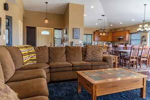 A living room with a sectional sofa, a coffee table, and a dining area with wooden chairs and a table.