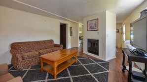 Ein Wohnzimmer mit Sofa, Couchtisch, Kamin und Fernseher.