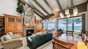 A spacious living area with a fireplace, a stone wall, and a view of the ocean. - Lakefront Beauty + On Water, Lakeland Village #610 (South Lake Tahoe)