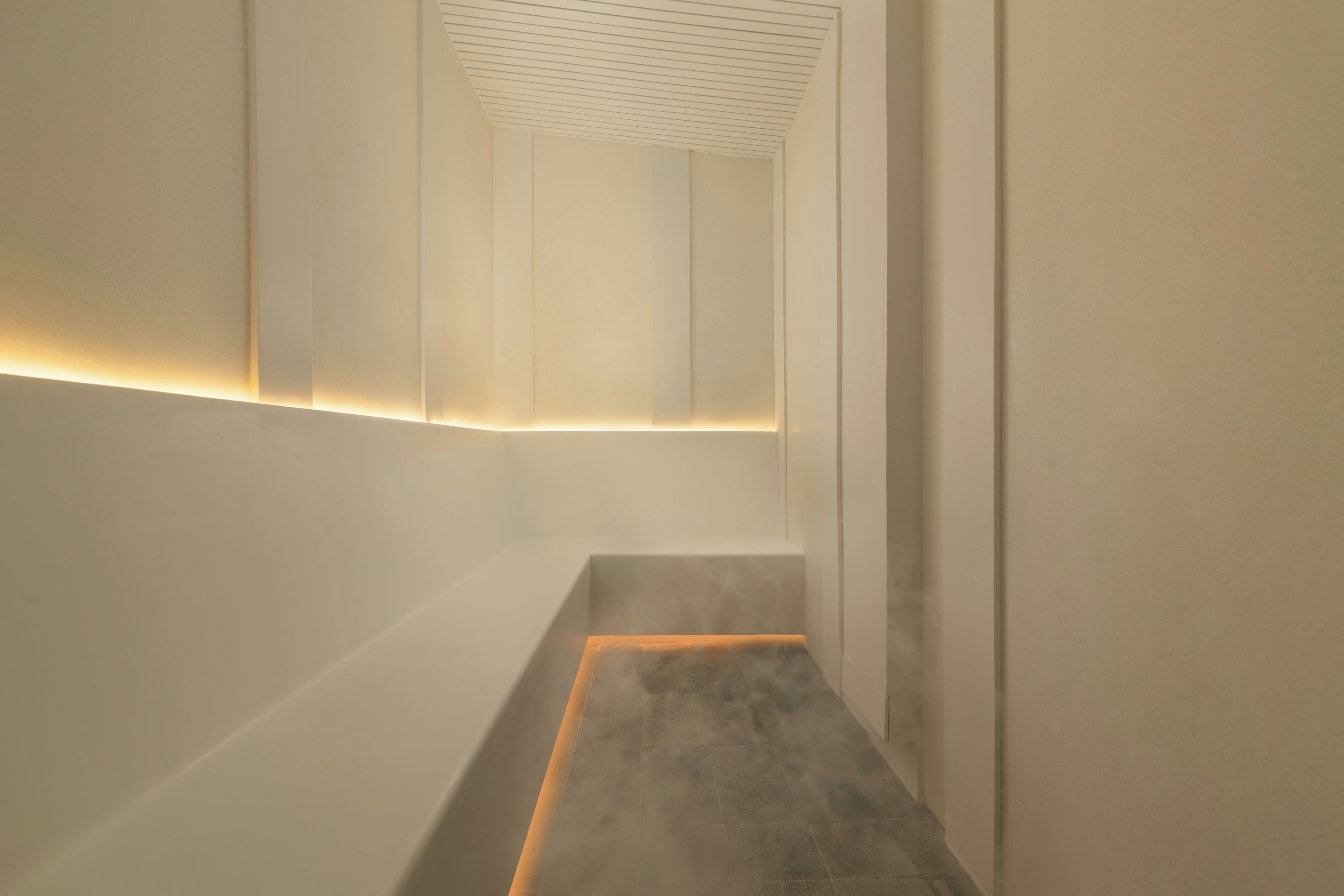 Een modern, minimalistisch interieur met een rechte, smalle gang die uitkomt op een overloop.