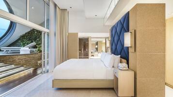 A modern hotel room with a large bed, a view of the outdoors, and a stone wall.