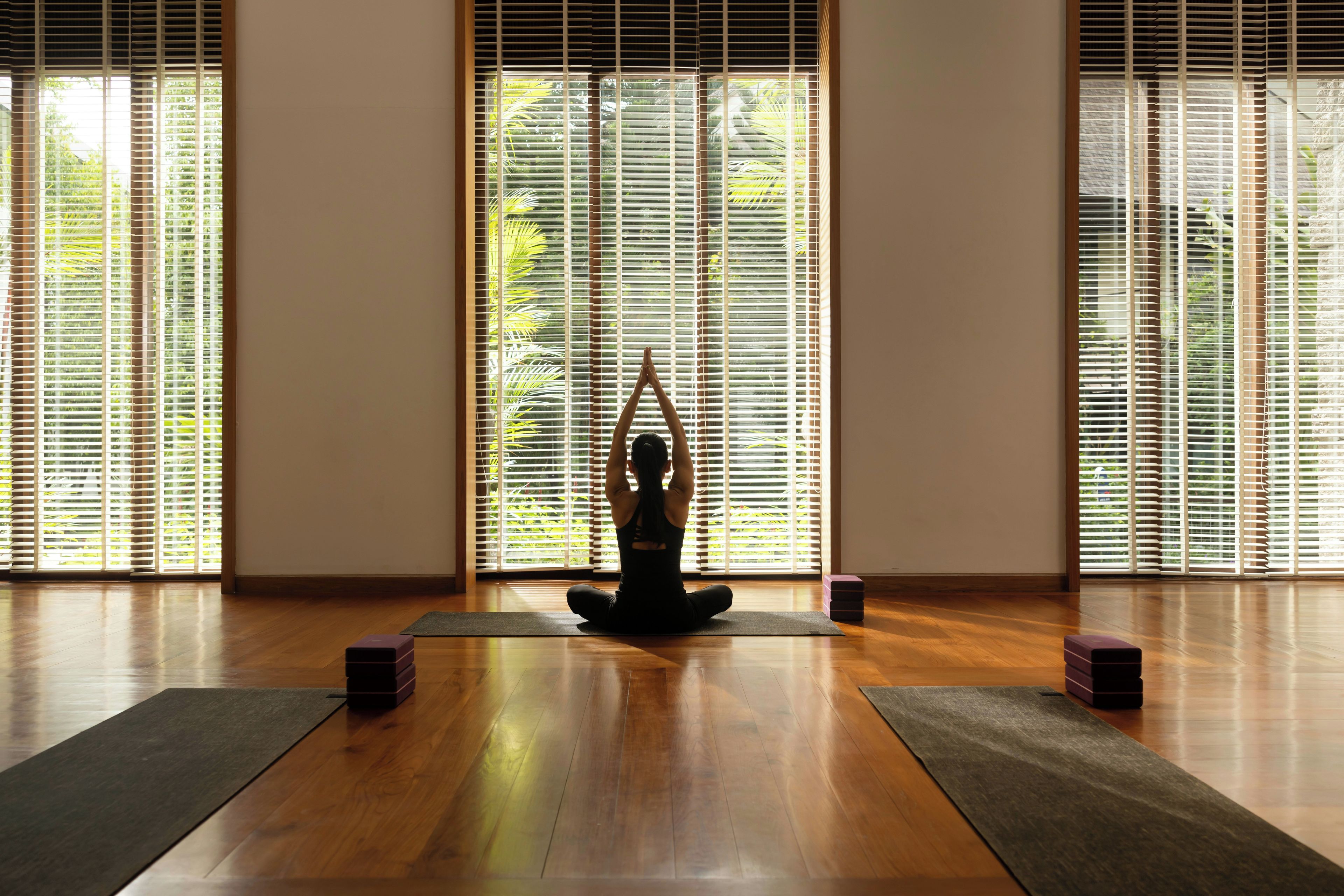 A room with wooden flooring, a yoga mat, and a statue.