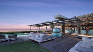 A modern outdoor lounge area with a pool, seating, and a pergola structure.
