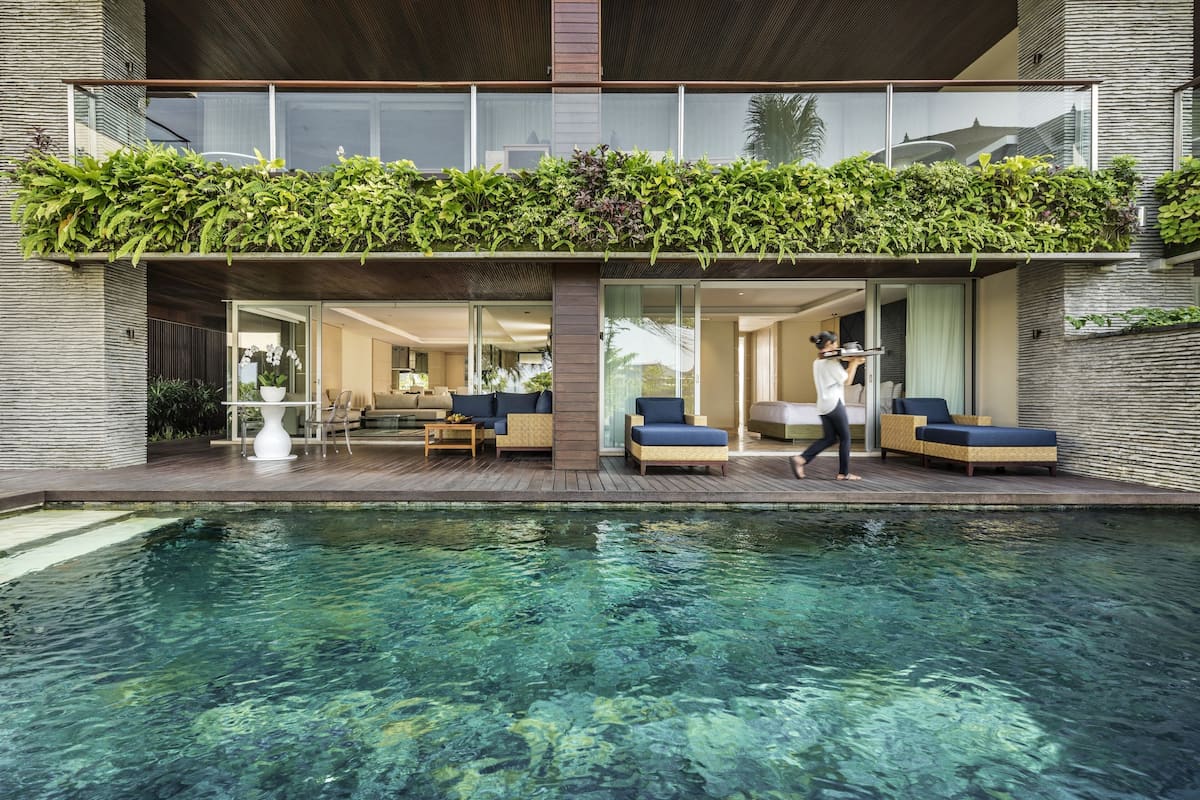 A modern house with a swimming pool, outdoor seating, and a balcony with plants.