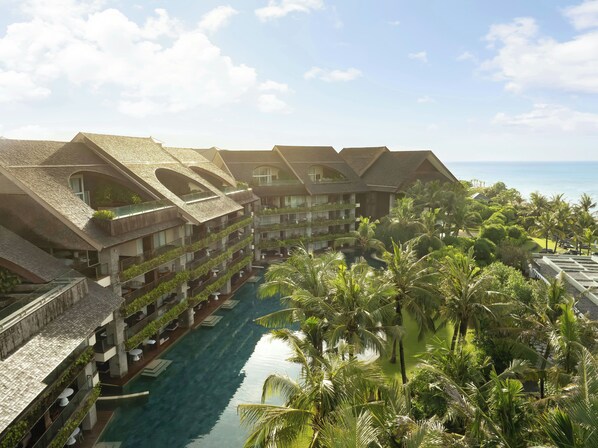 Un resort con edificios de varios pisos, una piscina central y abundante vegetación.