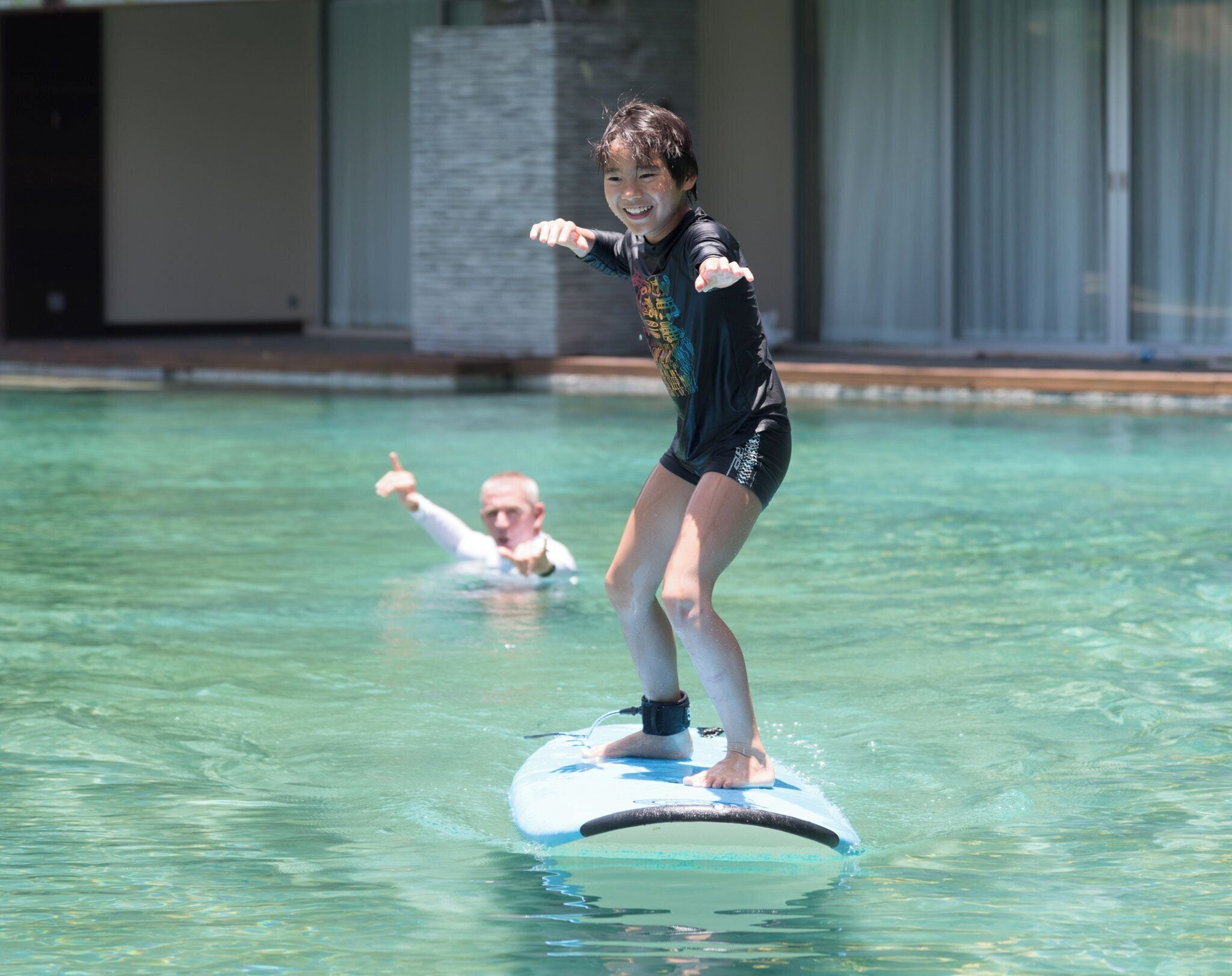 A person on a watercraft in a pool, with a building in the background.