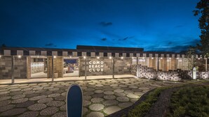 A modern building with a sign reading "COMO BEACH CLUB" at night. - COMO Uma Canggu (Canggu)