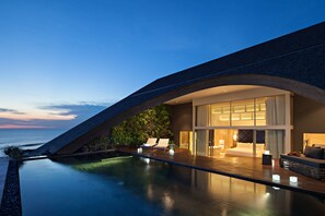 A modern hotel with a pool, lounge chairs, and a view of the ocean. - COMO Uma Canggu (Canggu)