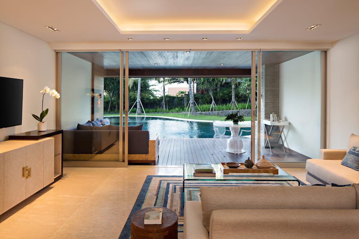 A modern living room with a large glass door leading to a pool area, a flat-screen TV, and a comfortable seating arrangement.