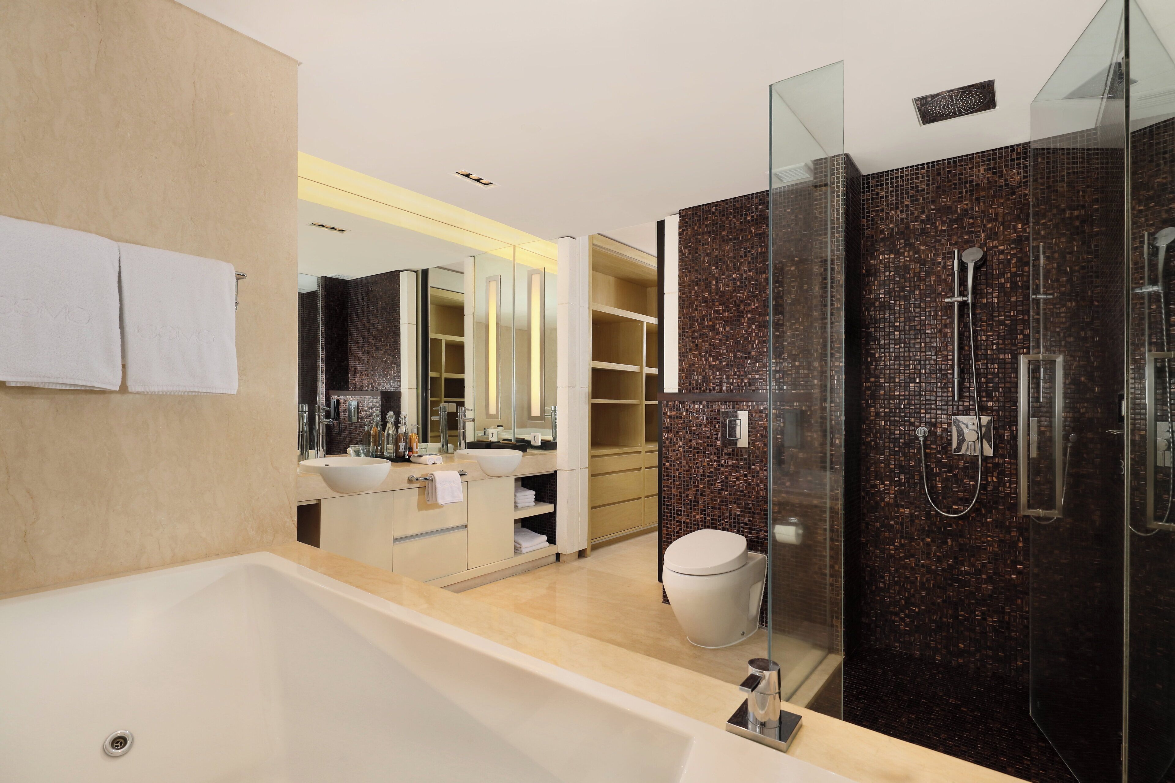 Un baño moderno con bañera, ducha con mampara de vidrio y un inodoro blanco.