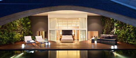 Ein modernes Hotelzimmer mit einem großen Bett, einer Sitzecke mit einer Couch und einem Poolbereich.