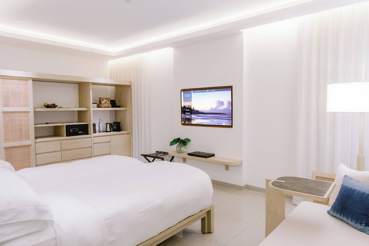 Una habitación de hotel moderna con una cama grande, un escritorio y una televisión montada en la pared.