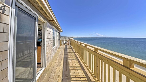 Eine Holzterrasse mit Geländer, die auf einen Strand blickt.