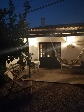 Un patio con una hamaca, un banco y una mesa.