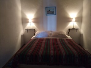 A room with a bed, two bedside lamps, a framed picture on the wall, and a patterned bedspread. -  Tia Luísa Cottage (country house) (Redondo)