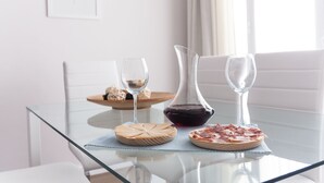 Een glazen tafel met drie borden eten, twee wijnglazen en een decanteerkannetje.