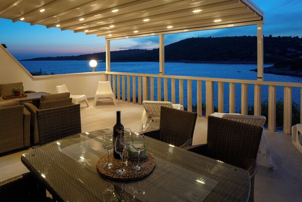 An outdoor seating area with a table, chairs, and a bottle of wine.