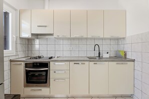 Una cucina moderna con forno a incasso, lavello e finestra per la luce naturale.