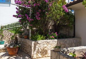 A stone retaining wall with potted plants and flowers.