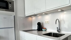 A modern kitchen with a built-in microwave, stainless steel appliances, a black coffee maker, and a sink.