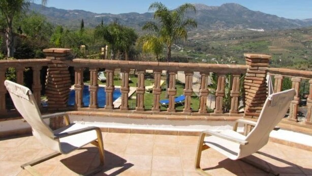 Ein Balkon mit zwei Liegestühlen, einem Pool und Bergblick.