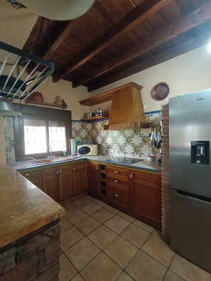 A kitchen with wooden cabinets, a stainless steel refrigerator, a microwave, and a sink. - Private villa with jacuzzi in Guaro (Guaro)